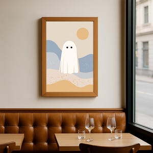 May include: A framed art print with a minimalist design. It depicts a white ghost with two black dot eyes, set against a beige sky, blue hills, and a yellow sun. The artwork is in a wooden frame, suitable for home decor.