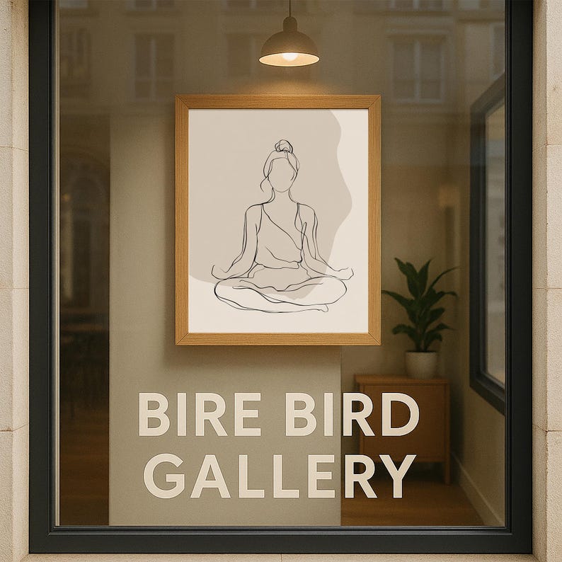 May include: A window display with a framed artwork showing a line drawing of a person in a yoga pose. The text "BIRE BIRD GALLERY" is displayed in white lettering. A small plant and a light fixture are also visible in the shop window.