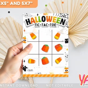 Puede incluir: Una tarjeta de juego de Tic-Tac-Toe con temática de Halloween con el título "HALLOWEEN TIC-TAC-TOE" en negro y naranja. El tablero del juego presenta gráficos de caramelos de maíz y calabazas. La tarjeta está sujeta por una mano y está disponible en tamaños de 8,89 cm x 12,7 cm y 12,7 cm x 17,78 cm.