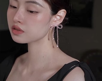 Pendientes con lazo de cinta de cristal, perla de Swarovski y pasadores de plata de ley.