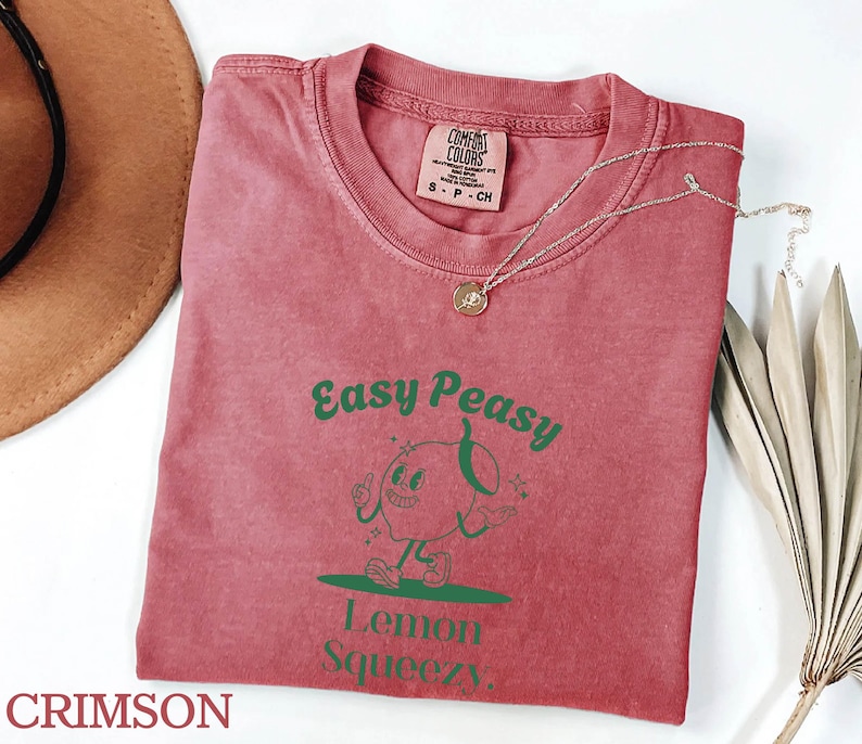 May include: Crimson red t-shirt with a green cartoon lemon character and the text "Easy Peasy Lemon Squeezy".