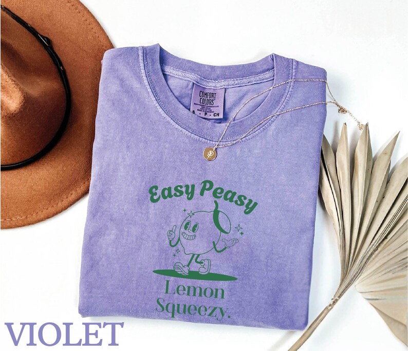 May include: A purple t-shirt with a green graphic of a cartoon lemon with the text "Easy Peasy Lemon Squeezy".