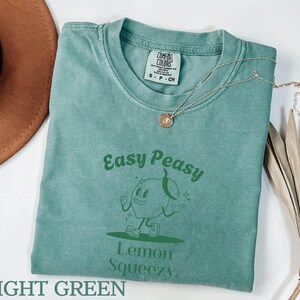 May include: Light green t-shirt with a green cartoon lemon character and the text "Easy Peasy Lemon Squeezy".