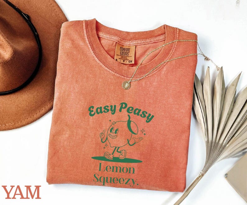 May include: A peach-colored t-shirt with a green graphic of a cartoon lemon with the text "Easy Peasy Lemon Squeezy."