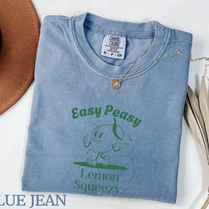 May include: A blue jean t-shirt with a green graphic of a cartoon lemon with the text "Easy Peasy Lemon Squeezy".