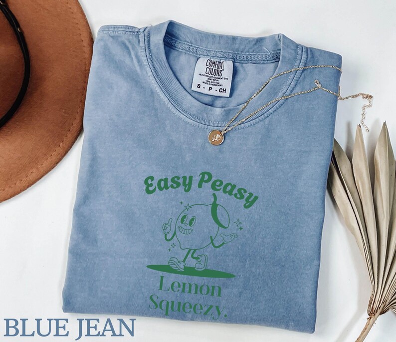 May include: A blue jean t-shirt with a green graphic of a cartoon lemon with the text "Easy Peasy Lemon Squeezy".