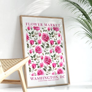 Pode incluir: Uma impressão emoldurada com um design floral com rosas cor-de-rosa e folhas verdes. A impressão tem o texto "FLOWER MARKET WASHINGTON, DC SYMBOLIC FLOWER: AMERICAN BEAUTY ROSE" na parte inferior.