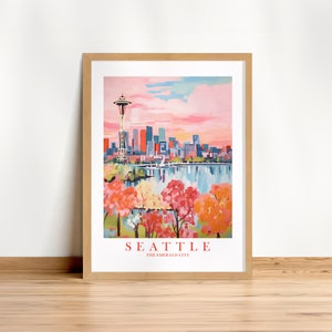 May include: A framed print of a colorful illustration of the Seattle skyline with the Space Needle, a body of water, and trees in the foreground. The text "SEATTLE THE EMERALD CITY" is at the bottom of the print.