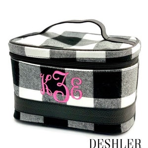 May include: Black and white buffalo plaid cosmetic bag with a black leather handle and trim. The bag has a pink monogram "K.Z.G." embroidered on the front.  DESHLER DESIGNS is printed on the bottom of the image.