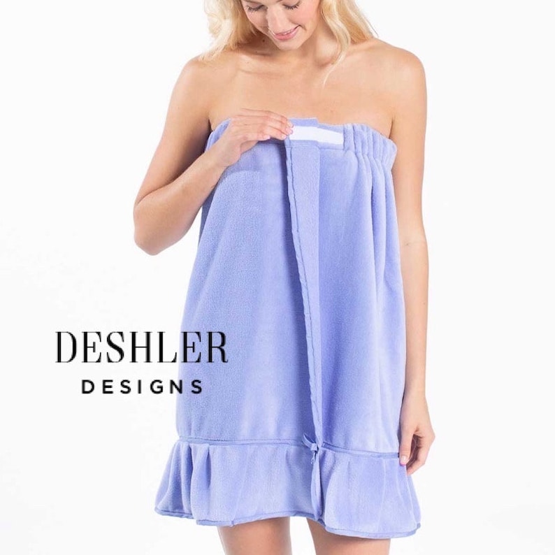 May include: A light purple spa towel wrap with a ruffled hem. The wrap is secured with a white velcro closure. The text "DESHLER DESIGNS" is printed in black.