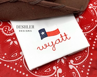 Puede incluir: Tela blanca con bordado rojo del nombre "wyatt" y una pequeña bandera de Texas bordada. La tela está sobre una bandana roja con lunares blancos.