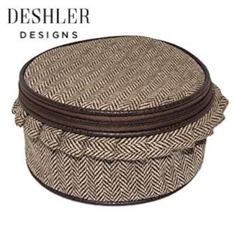 May include: Round brown and beige tweed fabric travel case with a zipper closure.