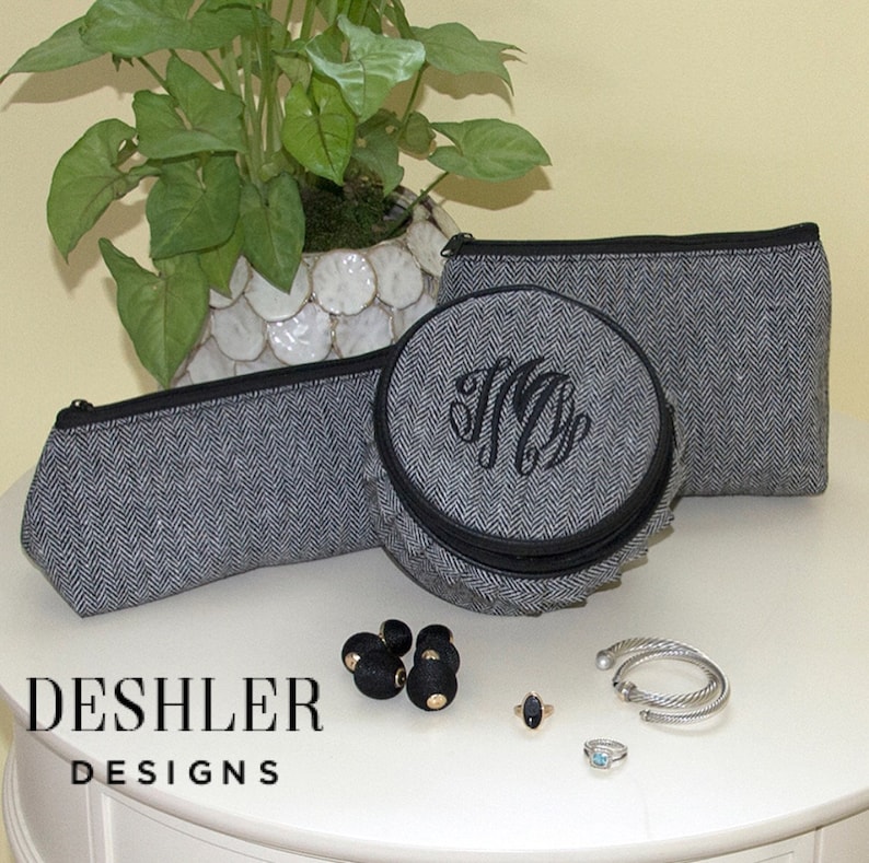 May include: Three gray and black zippered pouches with a herringbone pattern. The pouches are on a white surface with black beads, a ring, and two bracelets.