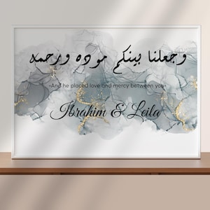 Può includere: Una stampa artistica incorniciata con calligrafia araba e testo inglese. L'opera presenta uno sfondo in stile acquerello nei toni del grigio e dell'oro. I nomi "Ibrahim & Leila" sono scritti in elegante corsivo.