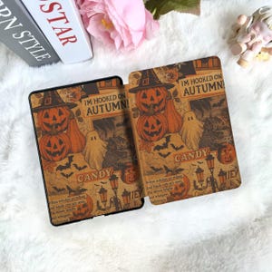 May include: Two Halloween-themed tablet cases with a vintage design. Each case features orange pumpkins, ghosts, bats, and the text "IM HOOKED ON AUTUMN!" and "CANDY" on a brown background. The cases are designed for a tablet.