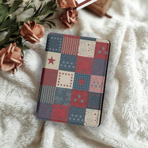 May include: A rectangular case with a patchwork design in red, white, and blue. The design features stars, stripes, and various patterns. The case is likely for an e-reader or tablet, with a black border.