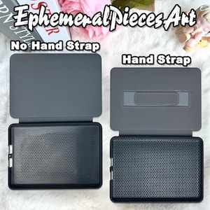 May include: Two gray tablet cases are displayed, one with a hand strap and one without. The cases are open, revealing a black interior with a honeycomb pattern. The text "Ephemeral Pieces Art" is at the top, with "No Hand Strap" and "Hand Strap" labeling each case.