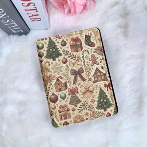 May include: A beige Christmas-themed tablet case featuring a repeating pattern of festive elements. The design includes Christmas trees, gift boxes, gingerbread men, bows, and ornaments in red, green, and gold.
