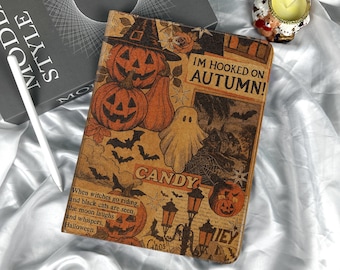 May include: A Halloween-themed journal with orange pumpkins, a ghost, and bats on a brown background. The text "IM HOOKED ON AUTUMN!" and "CANDY" are visible. The journal is on a white satin surface.