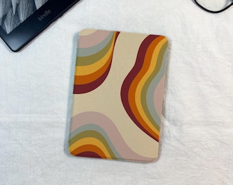 Puede incluir: Una funda protectora rectangular para lector electrónico con un patrón ondulado multicolor de rayas en color crema, verde salvia, amarillo mostaza, naranja y rojo oscuro. La funda tiene esquinas redondeadas y un acabado mate suave.