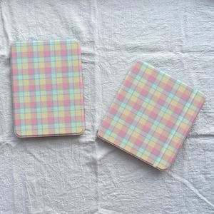 May include: Two rectangular cases in pastel shades with a plaid design. The cases have a grid pattern of light pink, yellow, blue, and green squares. They are shown on a white, textured background.