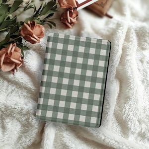 Könnte beinhalten: Ein rechteckiges Notizbuch oder Journal mit grünem und weißem Vichy-Muster. Das Cover hat ein klassisches Karomuster. Das Notizbuch liegt auf einer weichen, weißen, strukturierten Oberfläche, mit pfirsichfarbenen Rosen und Grünzeug im Hintergrund.