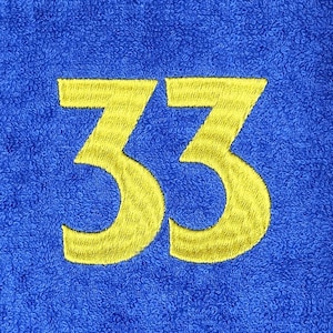 May include: A blue towel with the embroidered number 33 in yellow. The towel has a textured surface, and the yellow embroidery provides a contrasting pop of color against the blue background. The number is centered.