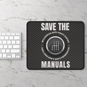 May include: A black and white mousepad with a carbon fiber pattern. It features a white circle with a gear shift pattern and the text "SAVE THE MILLENNIAL ANTI-THEFT DEVICE REAL CARS DON'T SHIFT THEMSELVES MANUALS".