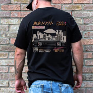 May include: Black t-shirt featuring a graphic of a black sports car with the text "Tokyo Turbo" and Japanese text. The design includes a cityscape and the text "Kyuumakagu 1997".