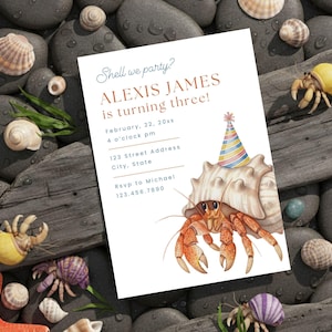 Può includere: Un invito di compleanno con il testo "Shell we party? ALEXIS JAMES is turning three!" con un'illustrazione ad acquerello di un paguro con un cappello da festa. L'invito è circondato da conchiglie e ciottoli.