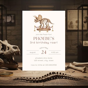 May include: A cream-colored invitation with a Triceratops skeleton illustration for Phoebe's 3rd birthday. The invitation includes the text "join the fossil fun!" and details for the party on August 24th at 4:00 PM.