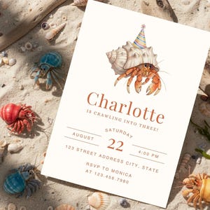 May include: A birthday invitation featuring a watercolor illustration of a hermit crab wearing a party hat, emerging from a seashell. The invitation reads "Charlotte is crawling into three!" with date, time, and RSVP information. The background includes sand, seashells, and other hermit crabs.