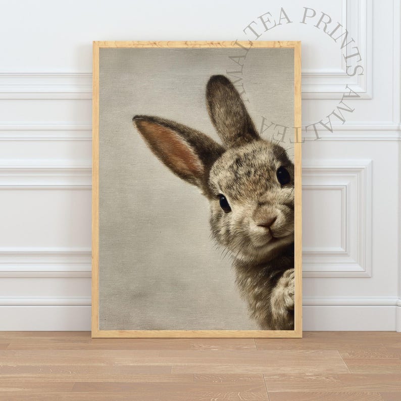 May include: A framed print featuring a close-up of a curious rabbit. The rabbit has brown and gray fur, with long ears and dark eyes. The print is in a light-colored wooden frame, perfect for a nursery or farmhouse decor.