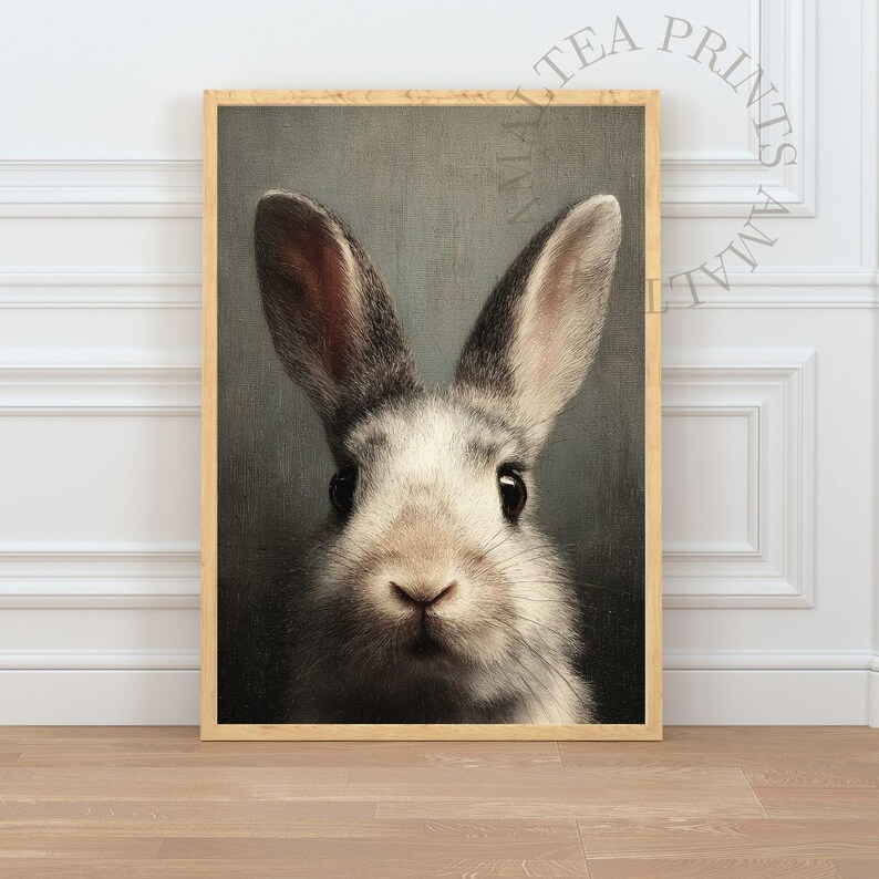 Op de afbeelding: Een ingelijste print met een close-up van het gezicht van een konijn. Het konijn heeft grijs en wit haar, grote oren en donkere ogen. De print zit in een houten lijst en heeft een vintage uitstraling, geschikt voor woondecoratie.