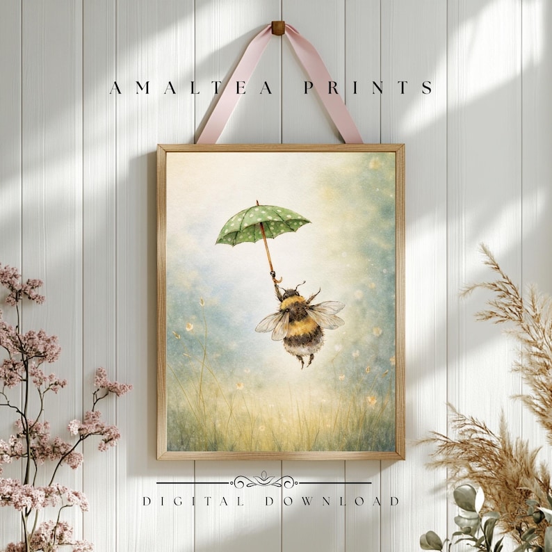 K&ouml;nnte beinhalten: Gerahmter Kunstdruck mit einer Illustration einer Hummel, die einen gr&uuml;nen, gepunkteten Regenschirm h&auml;lt und durch eine pastellfarbene Landschaft schwebt. Der Druck tr&auml;gt die Aufschrift "AMALTEA PRINTS" und "DIGITAL DOWNLOAD".