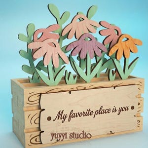 Peut inclure: Bo&icirc;te &agrave; fleurs en bois avec des fleurs d&eacute;coup&eacute;es au laser dans des tons de rose, orange et violet. La bo&icirc;te porte une enseigne d&eacute;corative en bois avec l'inscription "My favorite place is you" et le logo "yuyyi studio".