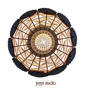 May include: Overhead view of a decorative wooden pendant light fixture. The light features a circular design with a central light bulb, surrounded by layered wooden elements in shades of brown and black. The text "yuyyi studio" is at the bottom.