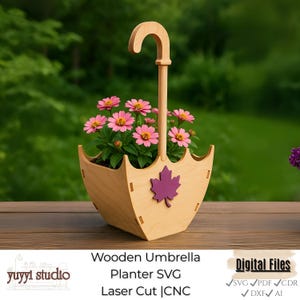 Puede incluir: Una jardinera de madera con forma de paraguas con un asa, que contiene flores rosas. Una hoja de arce púrpura está adherida a la parte delantera. El texto "Wooden Umbrella Planter SVG Laser Cut | CNC" está en la parte inferior.