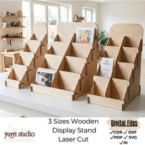 May include: Three wooden display stands of varying sizes, laser-cut from light-colored wood. Each stand has multiple tiered shelves for displaying items. The stands are empty, ready for use. Text on the image reads "3 Sizes Wooden Display Stand Laser Cut".