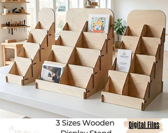 May include: Three wooden display stands of varying sizes, laser-cut from light-colored wood. Each stand has multiple tiered shelves for displaying items. The stands are empty, ready for use. Text on the image reads "3 Sizes Wooden Display Stand Laser Cut".