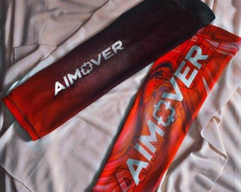 Pode incluir: Duas mangas de braço vermelhas e pretas com a palavra "AIMOVER" impressa em branco. As mangas são feitas de um material elástico e têm um padrão sutil.
