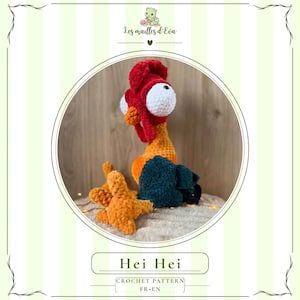 May include: A plush crochet toy of a rooster with large white eyes, a red comb and wattle, an orange neck, and dark teal wings. The toy has textured yarn and orange feet. The text Hei Hei and Crochet Pattern FR EN is visible below the image.