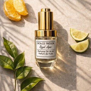 Op de afbeelding: Een parfumolie flesje met een gouden dop en een label met de tekst "DOLCE TRÉSOR Regal Apex Perfume Oil 30 ml Parfum de Huile." De afbeelding bevat sinaasappelschijfjes, limoenpartjes en groene bladeren, wat wijst op een citrusgeur.