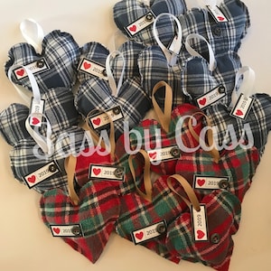 May include: A collection of handmade plaid heart ornaments with a red heart and the year 2019 printed on each. The ornaments are made from repurposed flannel fabric and are perfect for adding a touch of rustic charm to your holiday decor.