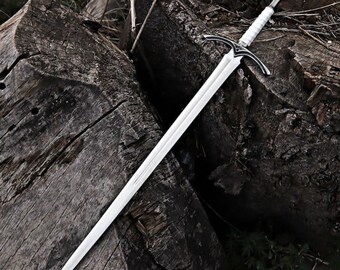 May include: A silver sword with a white handle and a crossguard. The blade is long and sharp, and the sword is resting on a weathered wooden surface. The sword has a rounded pommel.