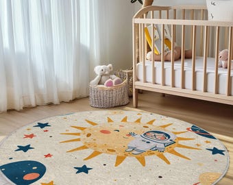 Puede incluir: Una alfombra redonda de color crema con un sol amarillo, un astronauta azul y estrellas. La alfombra es perfecta para una guardería o una sala de juegos.