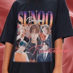 Op de afbeelding: Zwart T-shirt met een afbeelding van het woord "SUNOO" in een kleurrijk retro-lettertype, met de tekst "Enhypen" eronder. Het shirt toont afbeeldingen van verschillende mensen. Het woord "Faixstore" is ook zichtbaar.