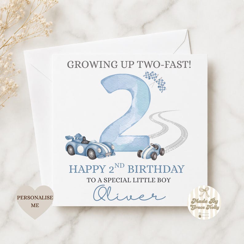 Puede incluir: Una tarjeta de cumplea&ntilde;os cuadrada con un gran n&uacute;mero dos en acuarela azul claro, dos coches de carreras azules, una bandera a cuadros y marcas de neum&aacute;ticos. El texto dice: GROWING UP TWO-FAST! HAPPY 2ND BIRTHDAY TO A SPECIAL LITTLE BOY Oliver.