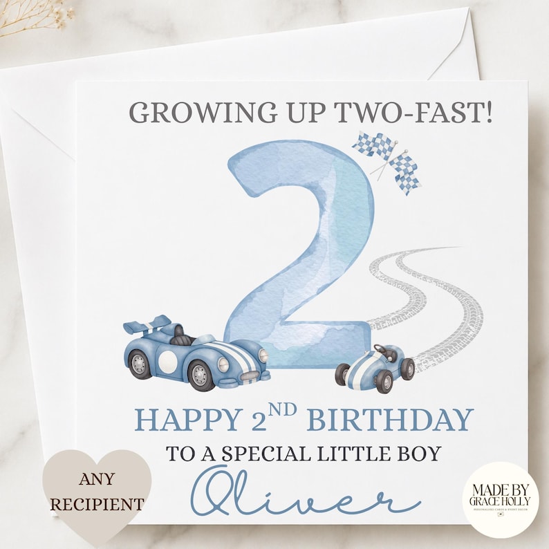 Puede incluir: Una tarjeta de felicitaci&oacute;n cuadrada con un n&uacute;mero dos grande en acuarela azul claro, dos coches de carreras azules y banderas a cuadros. El texto dice: GROWING UP TWO-FAST! HAPPY 2ND BIRTHDAY TO A SPECIAL LITTLE BOY Oliver. Incluye huellas.