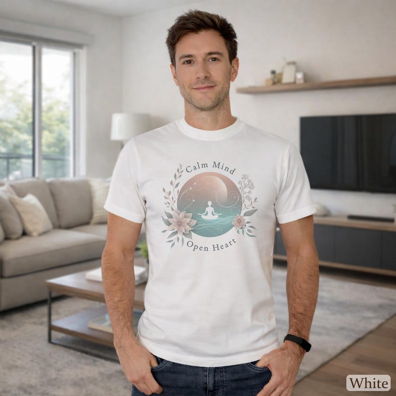 Puede incluir: Camiseta blanca con un dise&ntilde;o gr&aacute;fico circular que presenta una figura meditando, rodeada de elementos florales y el texto "Calm Mind Open Heart". El dise&ntilde;o incorpora colores pastel y una est&eacute;tica serena.